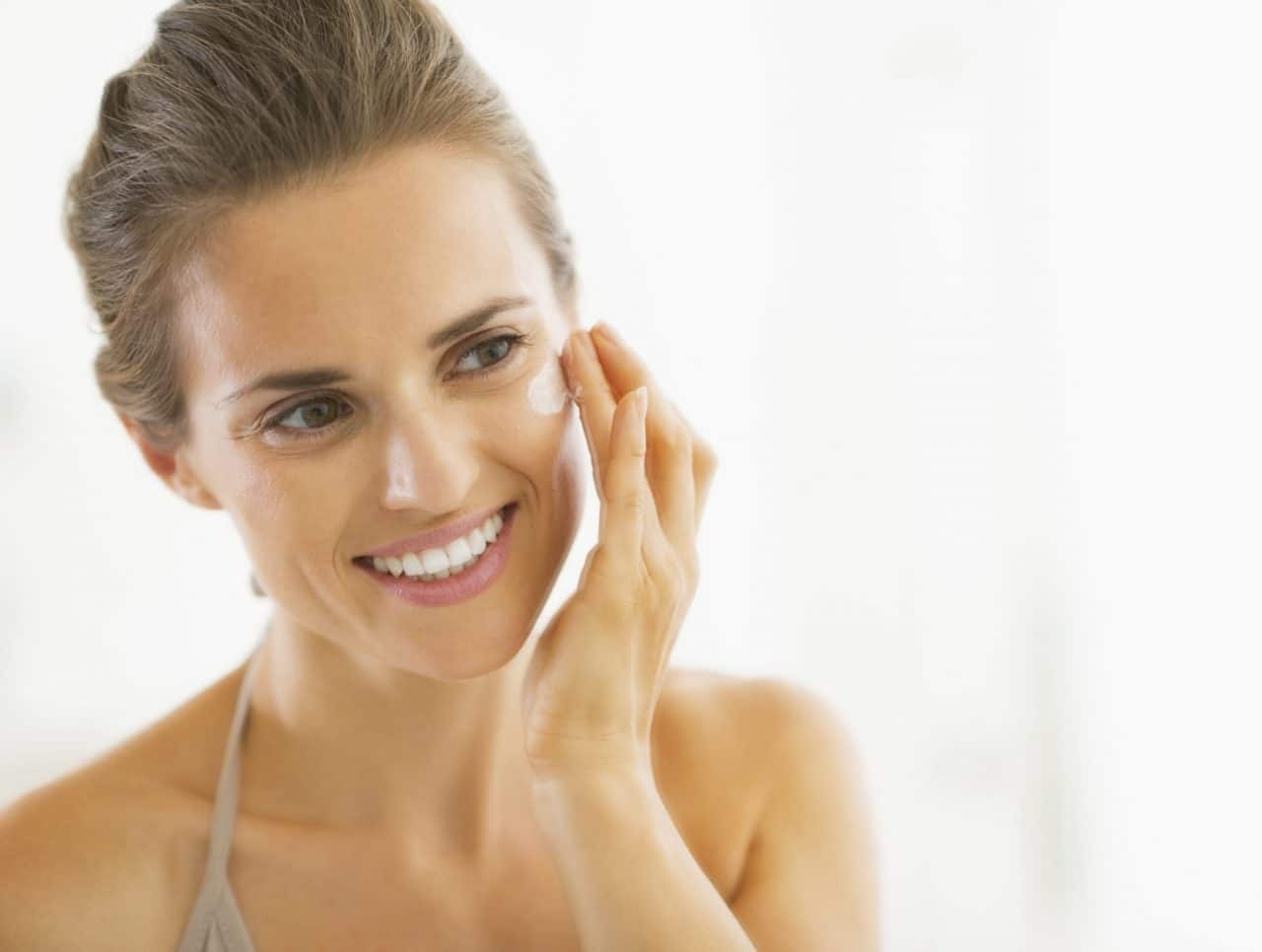 Person applying a cream on their cheek