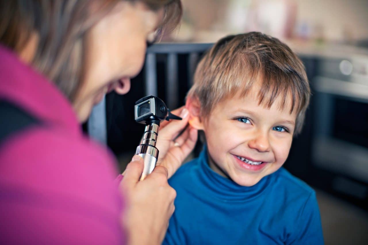 A smiling child getting an otoscope examination