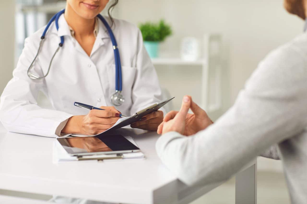 Female doctor therapist gross allergist nutritionist otolaryngologist and male patient sitting at a table in a clinic office. Medicine clinic hospital.