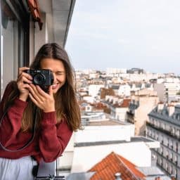 Woman taking a photo from a veranda while traveling.
