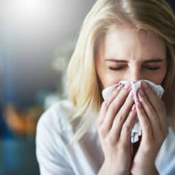 Woman with allergies blows nose