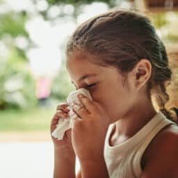 Young girl with allergies blowing her nose