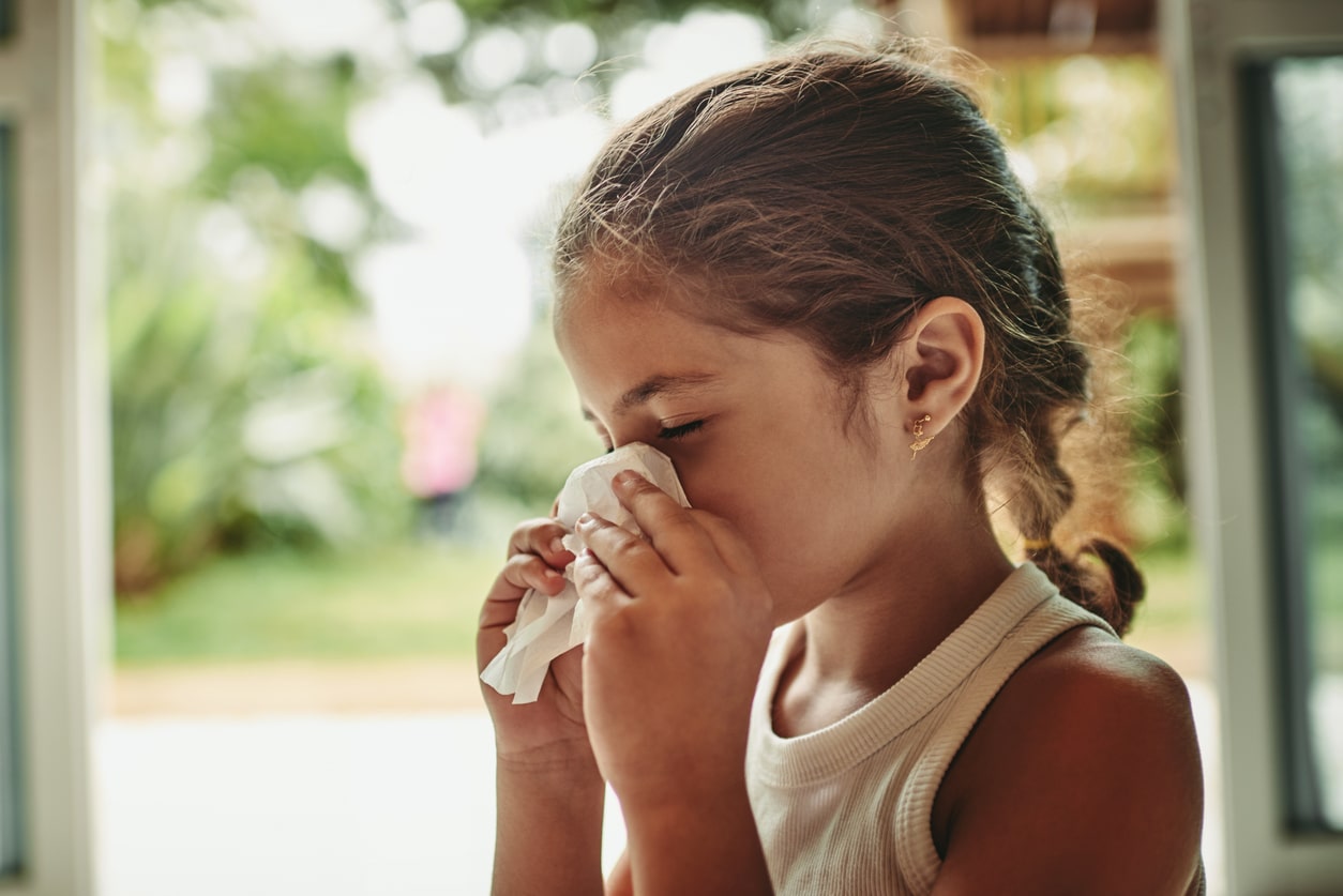 Young girl with allergies blowing her nose.
