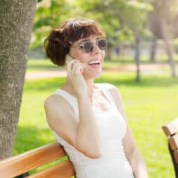 Happy woman talking on the phone on a bench in the park