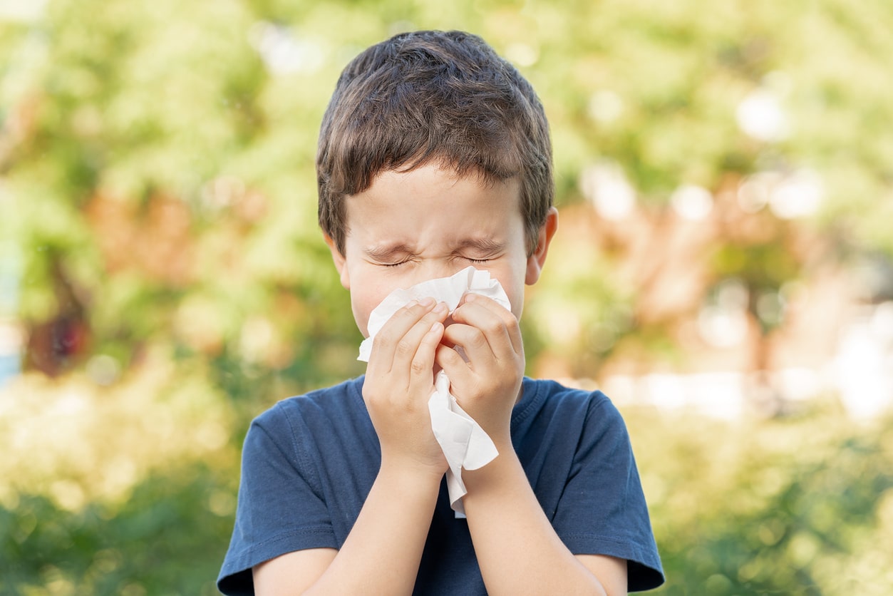 Child sneezing outdoors.