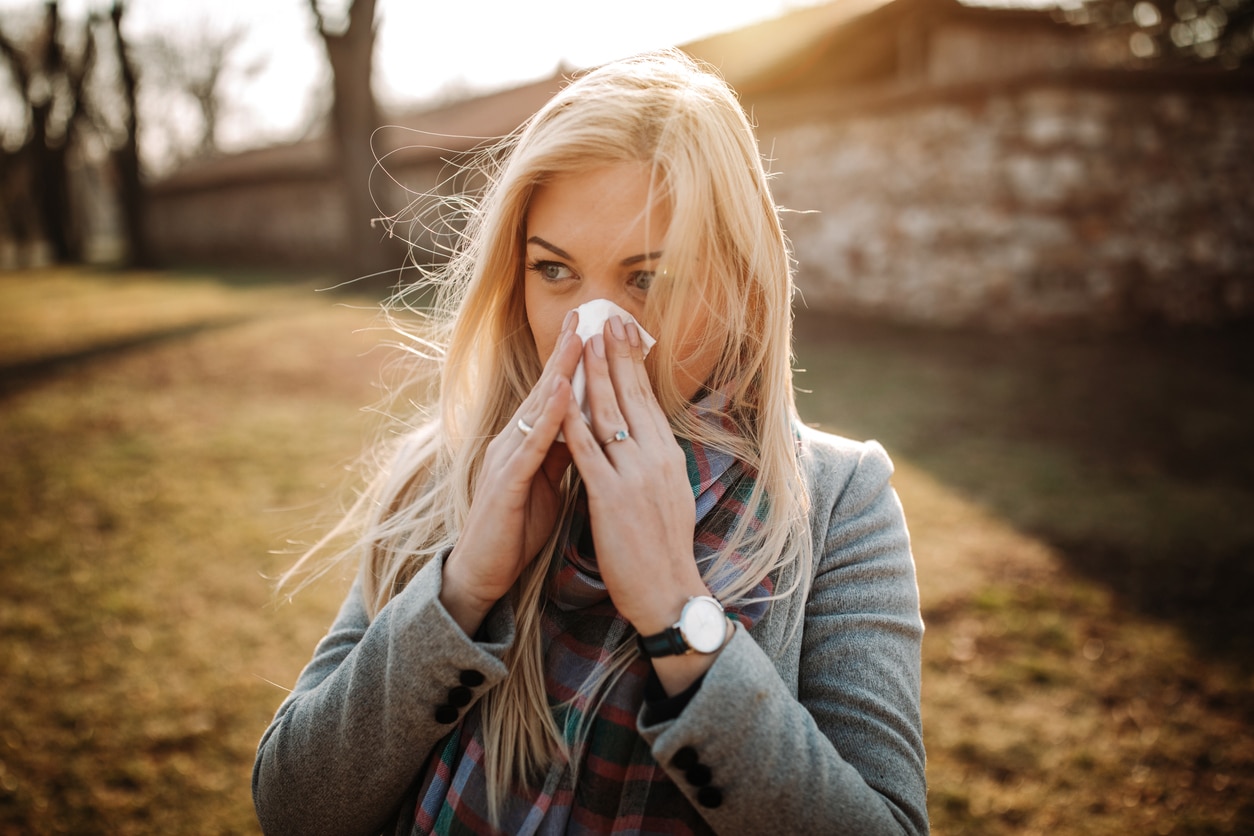 Woman with fall allergies blowing her nose.