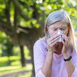 Senior woman sneezing at the park