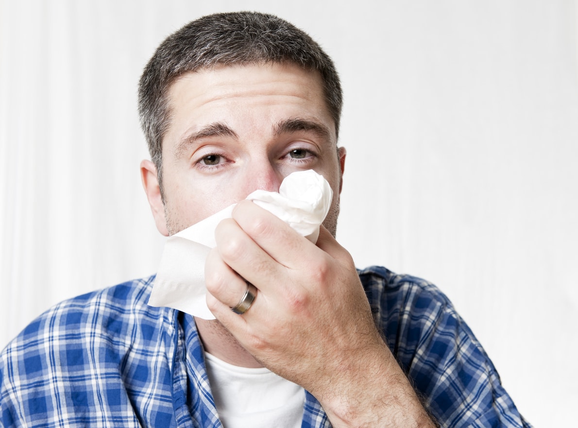 Man at home blowing his nose into a tissue