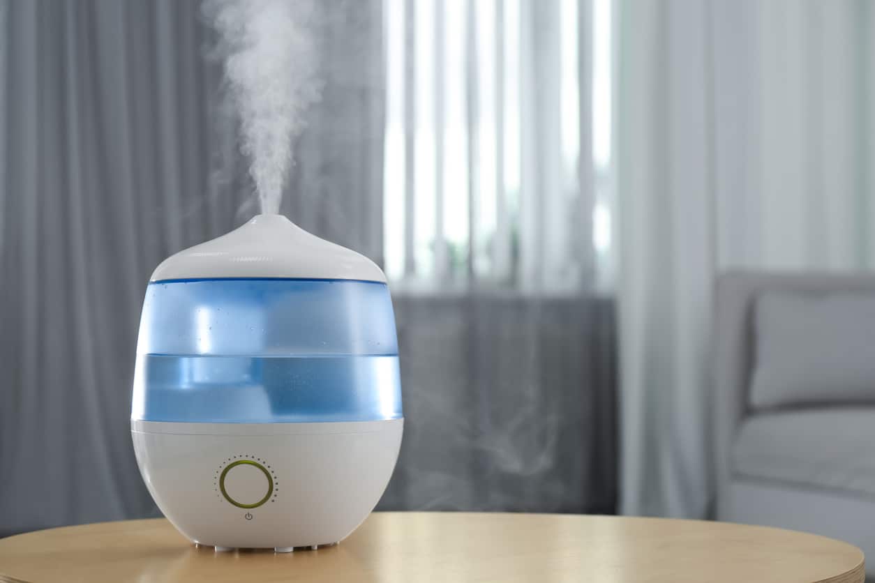 Humidifier on a table emitting water vapor into the air.